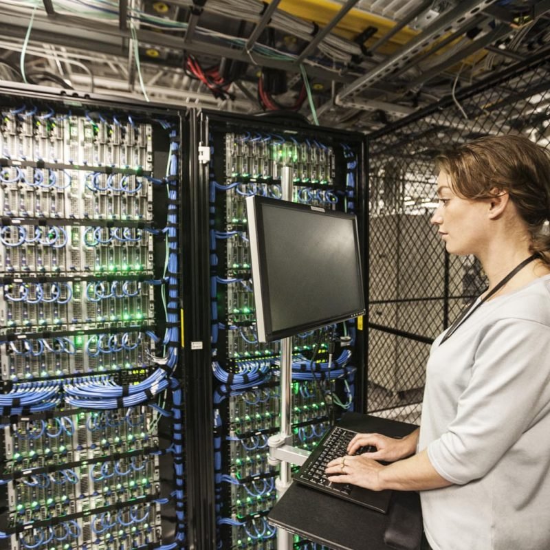 Caucasian woman technician doing diagnostic tests  on computer servers in a server farm.