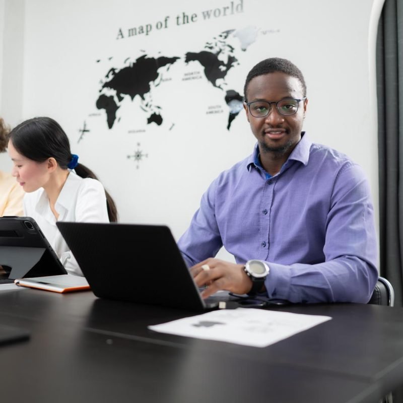 Multiethnic team of architects and designers are meeting to brainstorm design an application smartphone on a bright modern office working on a laptop.